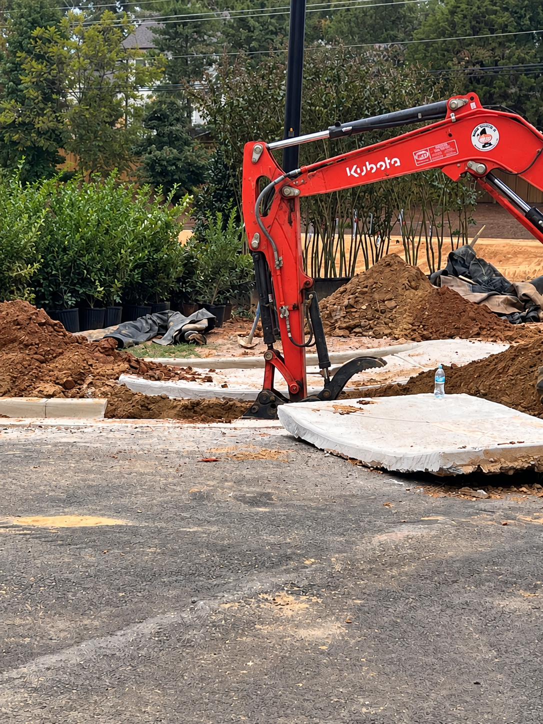 Excavator lifting concrete to access the road-crossing sleeves